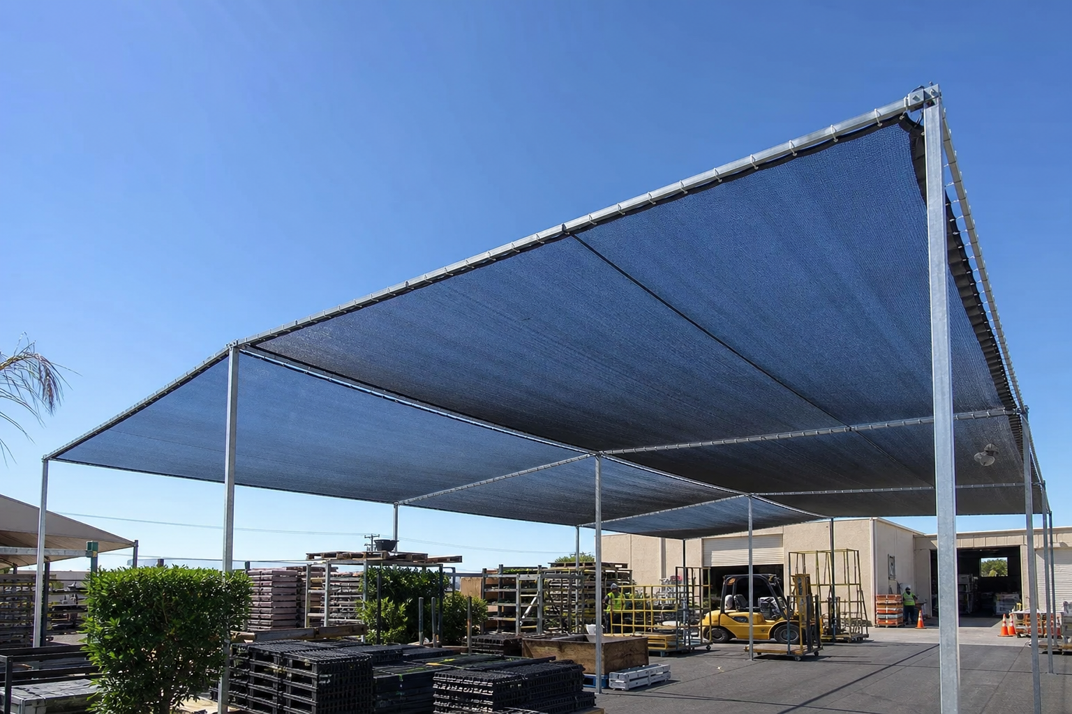 Large custom mesh tarp panels installed for shade and ventilation in an outdoor industrial yard