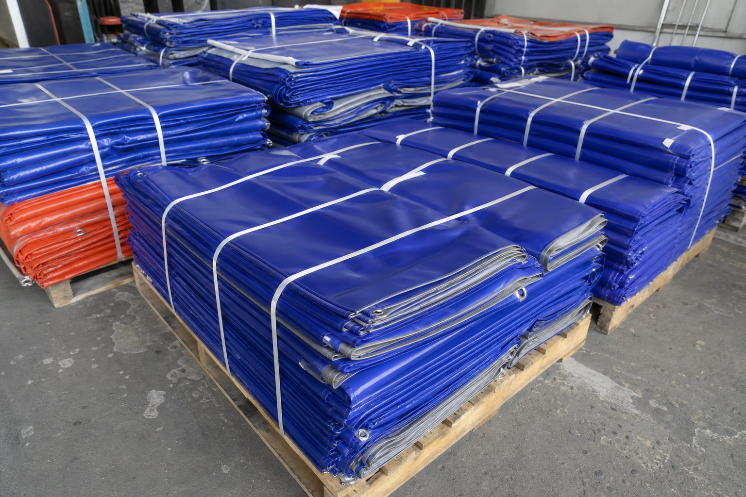 Folded custom PVC tarps labeled and packed on pallets for bulk export shipment