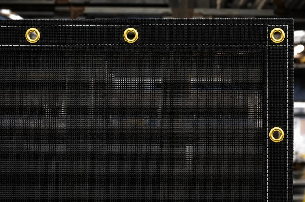 Black mesh tarp with a reinforced stitched edge and brass eyelets