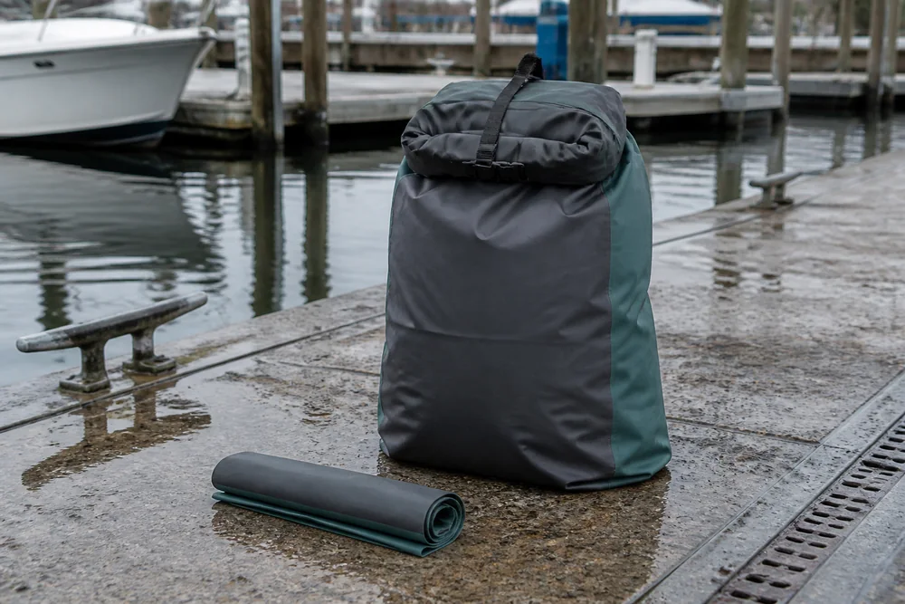 Unbranded waterproof dry bag made from thin flexible coated technical fabric beside a wet dock
