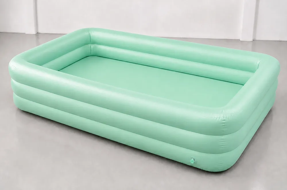 Light green rectangular inflatable pool with visible welded seams and a valve